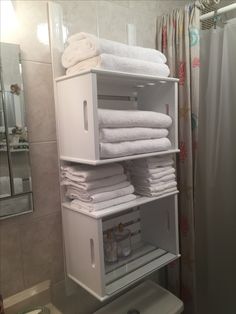 towels are stacked on top of each other in a bathroom cabinet next to a toilet