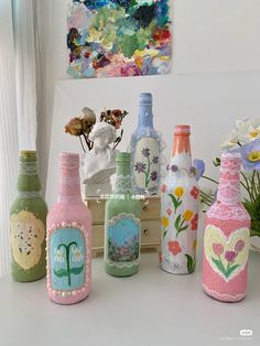 there are many different colored bottles on the table next to each other and one is painted with flowers