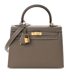 This is the authentic HERMES Epsom Kelly Sellier 25 in Etoupe. This classic Kelly handbag tote is crafted of luxuriously textured calfskin leather in taupe. The bag features a sturdy rolled leather top handle, an optional shoulder strap, and a crossover flap and strap closure with gold plated hardware including a padlock with a clochette for the keys. This opens to a goatskin leather interior with zippered and flat pockets. Kelly 25 Hermes, Hermes Bags Kelly, Kelly Hermes Bag, Hermes Etoupe, Kelly Handbag, Hermes Kelly 25, Kelly Sellier, Hermes Birkin 25, Kelly Bag