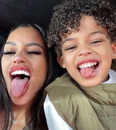 a woman and child sticking their tongues out in the back seat of a car together