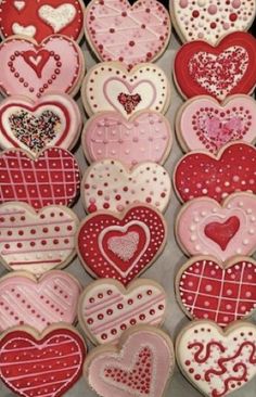 heart shaped cookies are arranged in rows on a baking sheet, ready to be decorated