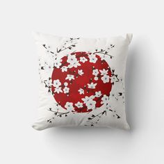 a red and white pillow with cherry blossoms on the front, against a white background