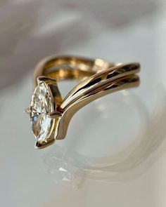 a yellow gold ring with an oval cut diamond in the center, on a white surface