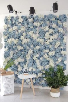 a large blue and white flowered wall hanging on the side of a room with two potted plants in front of it