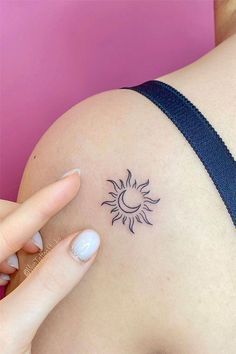 a woman's arm with a small sun tattoo on the back of her shoulder