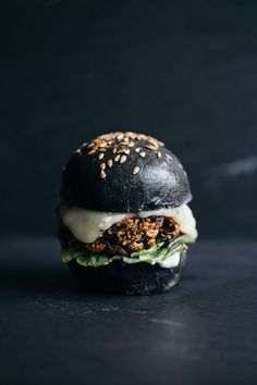 a black burger with lettuce, cheese and other toppings