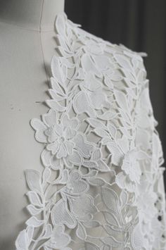 the back of a white dress with flowers on it's chest and lace detailing