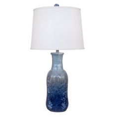 a blue vase lamp with a white shade on the base and a light in front of it