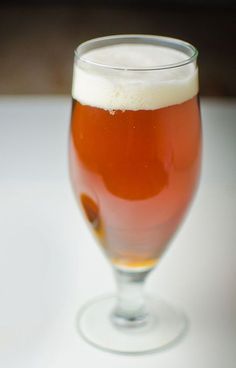 a glass filled with beer sitting on top of a table