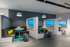 the interior of a restaurant with multiple tables and chairs, two large monitors on the wall