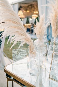 two clear vases sitting on top of a glass table covered in white pamodia