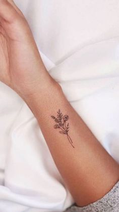 a woman's arm with a small flower tattoo on the left side of her wrist