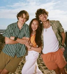 three young people standing next to each other on a beach