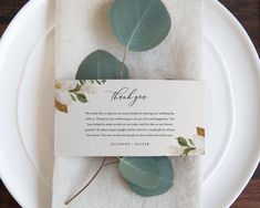 a white plate topped with green leaves and a thank you card