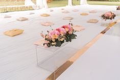 flowers are placed in clear vases on top of the tables at an outdoor wedding