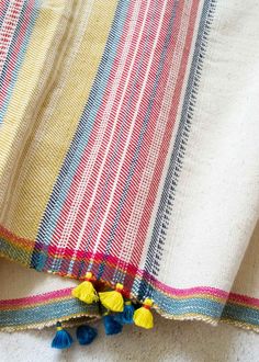 a multicolored striped fabric with tassels and pom - poms