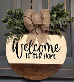 a welcome sign hanging from the side of a door with a bow on it that says welcome to our home