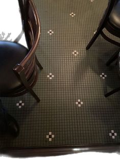 two wooden chairs sitting next to each other on a tiled floor