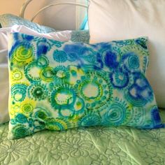 a green and blue pillow sitting on top of a bed