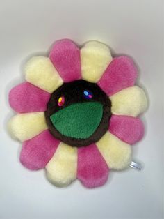 a pink and yellow flower with green center on a white background, it appears to be made out of felt