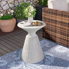 a white table sitting on top of a blue rug next to a potted plant