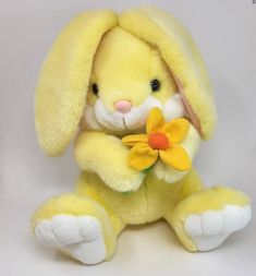 a yellow stuffed rabbit with a flower in its mouth