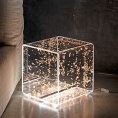 an illuminated cube on the floor in front of a couch