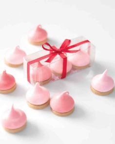 a box filled with pink frosted cookies next to a red ribbon tied around it