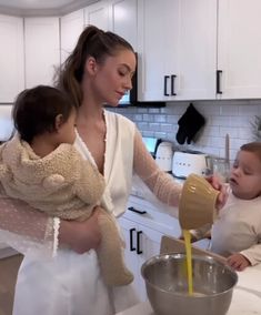 a woman holding a baby and mixing something in a bowl