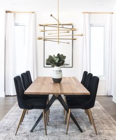 a dining room table with black chairs and a white rug