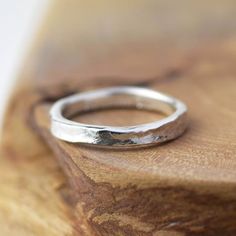 a silver ring sitting on top of a wooden table next to a piece of wood