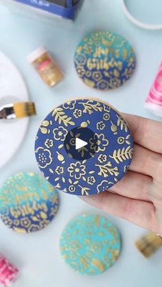 a person is holding a donut that has been decorated with gold and blue designs