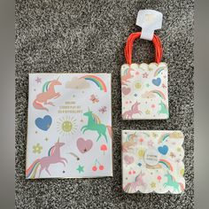 two small bags with unicorns on them sitting next to a card holder and envelope