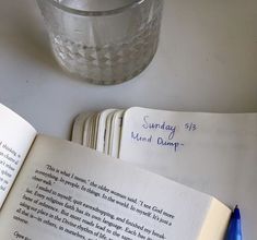 an open book sitting on top of a table next to a glass filled with water