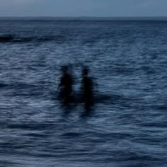 three people standing in the ocean at night