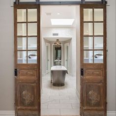 an open door leading to a bathroom with a tub in the middle and two windows