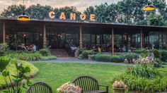 an outdoor restaurant with tables and chairs in the grass