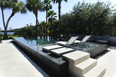 an outdoor pool with lounge chairs and palm trees in the background, surrounded by concrete steps