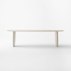 an oval white table with curved legs on a plain white surface in front of a wall