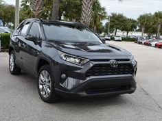 a black toyota rav parked in a parking lot with palm trees and other cars