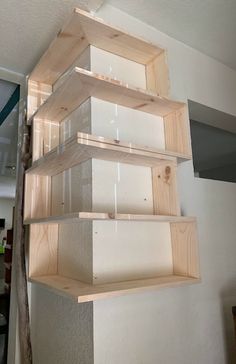 three wooden shelves are stacked on top of each other in the corner of a room