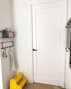 a white door in a small room with yellow step stools on the hardwood floor