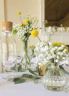 several vases with flowers in them sitting on a white tableclothed table cloth