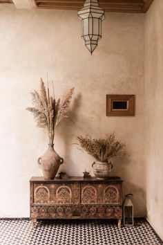 two vases on top of a table in a room with black and white tile flooring