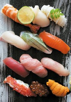 an assortment of sushi on a black plate