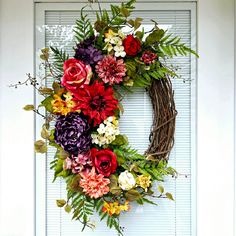 a wreath with flowers hanging on the front door