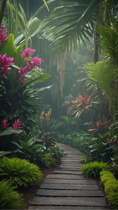 a pathway in the middle of tropical plants and trees with pink flowers on each side