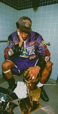 a man sitting on top of a toilet in a bathroom next to a trash can