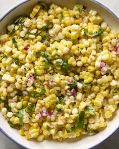 a bowl filled with corn and garnish on top of a table