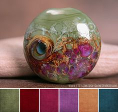 a green glass bead sitting on top of a table next to color swatches